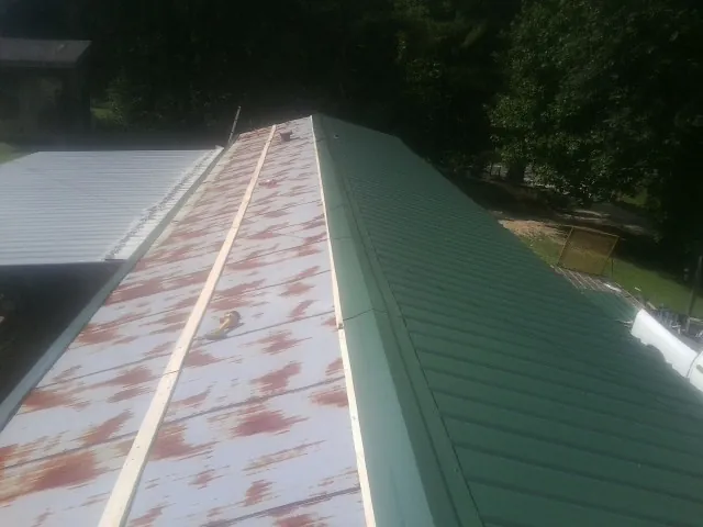 Old rusted panels beside newly installed green metal roofing — Wind Damage Roof Repair by Roofing Brothers in Old Lyme
