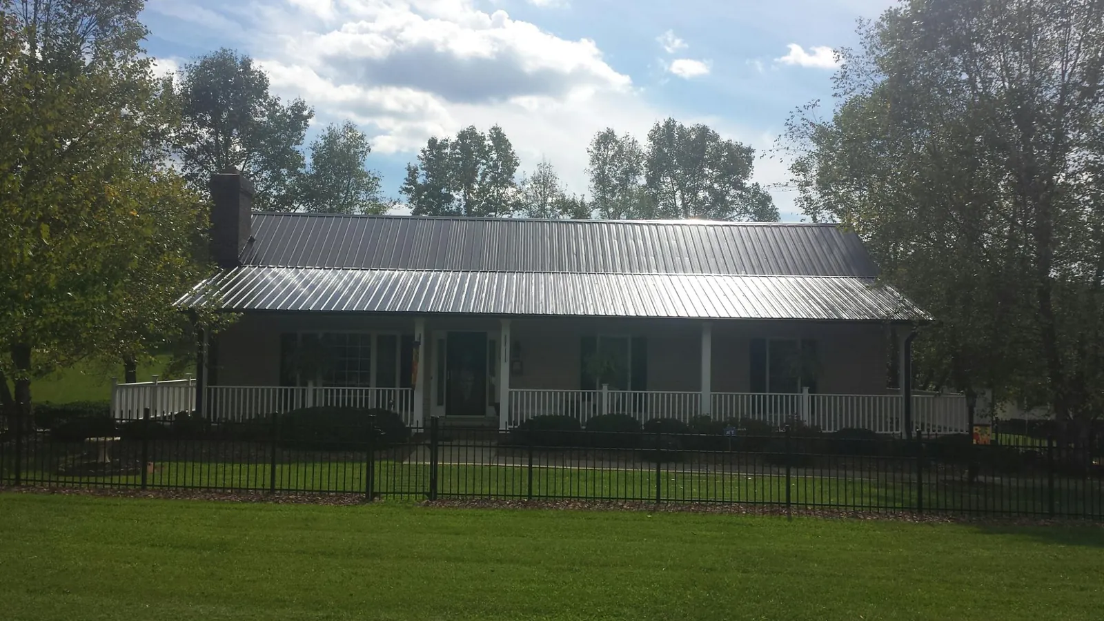 Gray metal roof on a brick ranch with a full width front porch — Gutter Guard Installation work by our crew in Old Lyme