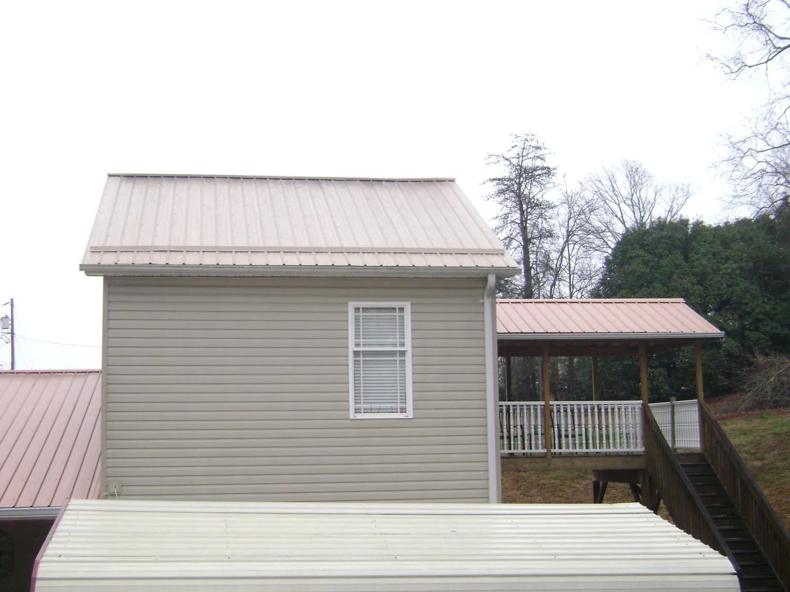 Tan metal roofs on a two story addition and attached porch, from a Roof Replacement job in Old Lyme