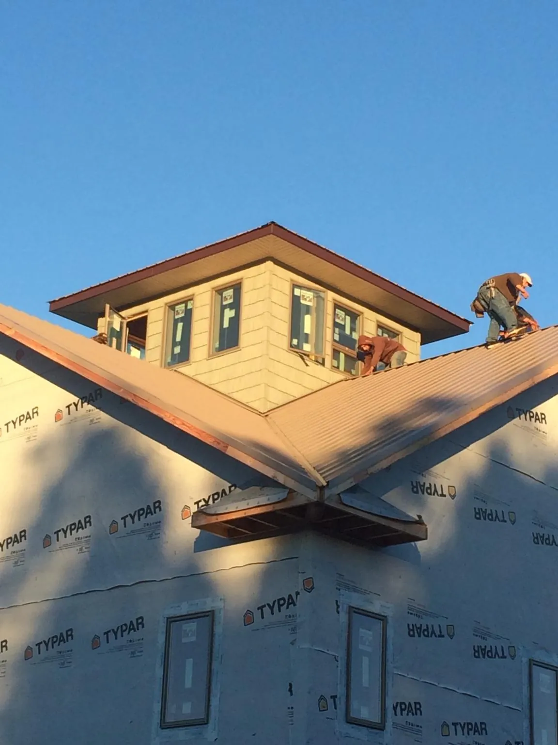 Roofers working around a rooftop cupola on a new metal roof at sunset — Roof Waterproofing in Old Lyme by Roofing Brothers